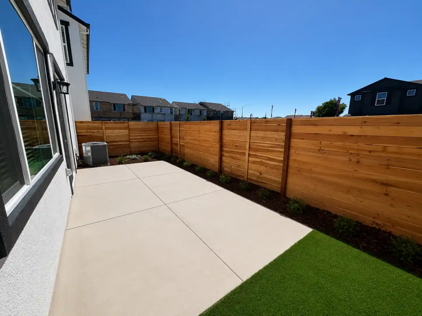 A fenced in yard with a wood fence and a house in the background.