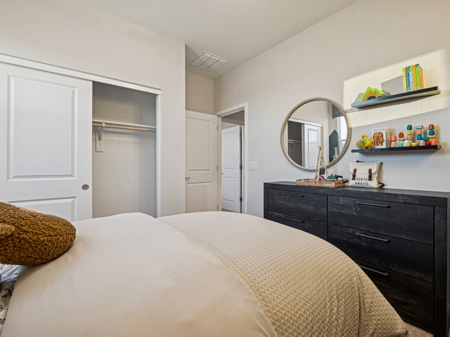 A bedroom with a bed and a mirror.