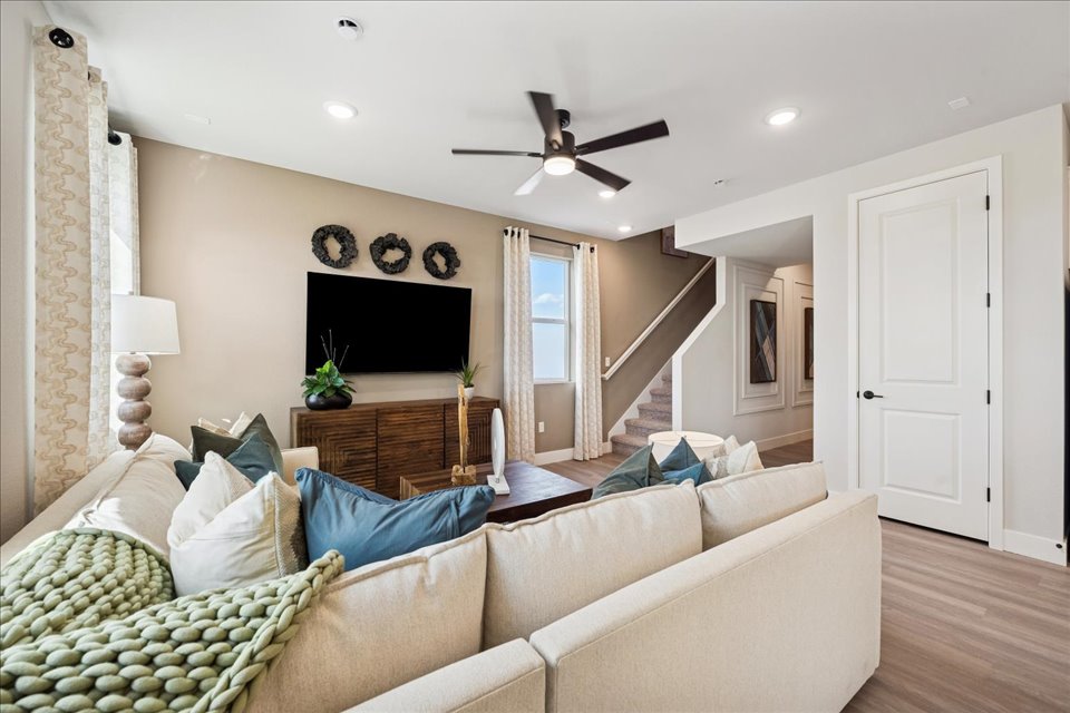 A living room with a couch and a fan.