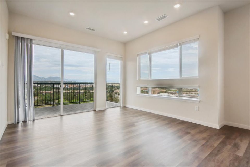 A room with a wood floor and a large window with a view of the ocean.
