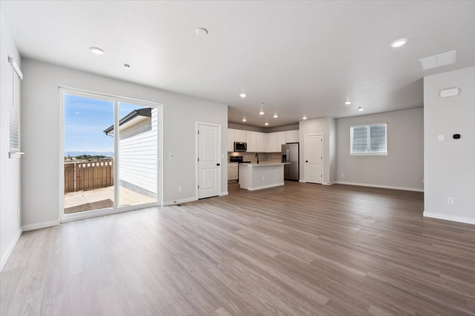 A large empty room with a wood floor and a large glass door.