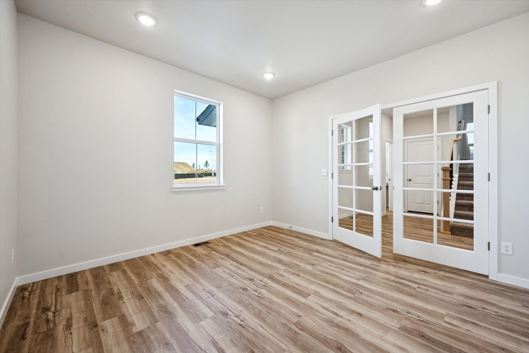 A room with a wood floor and a white door with a window.