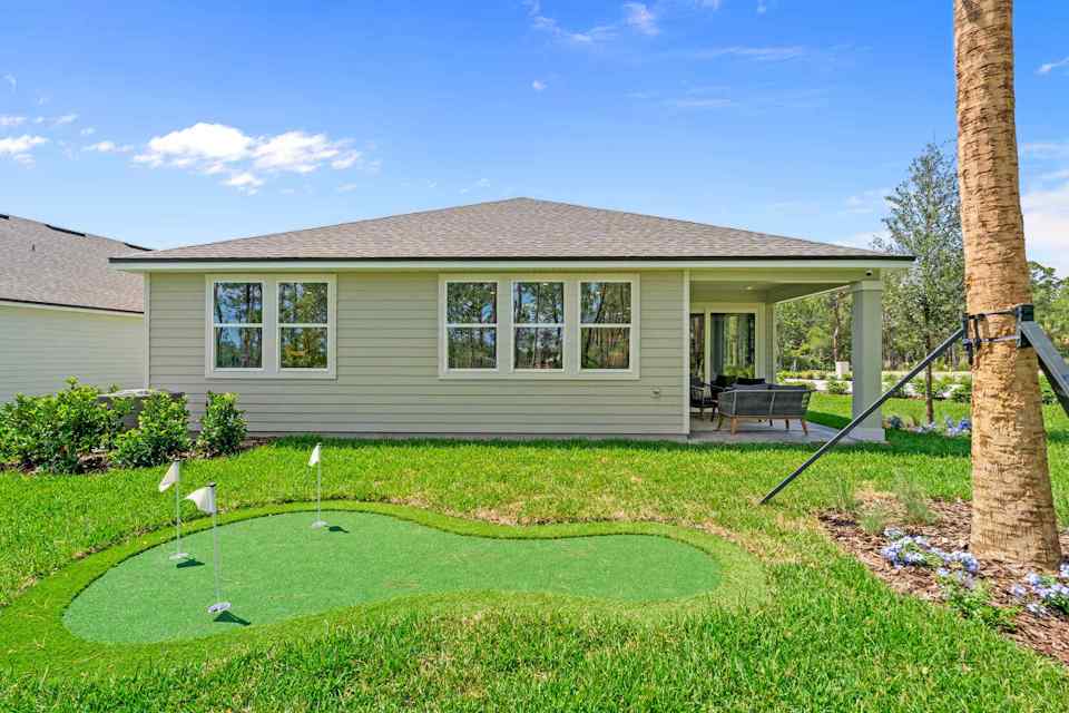 Coronado Model Home Backyard with Covered Patio and Small Putting Green at Reserve East in Flagler Beach