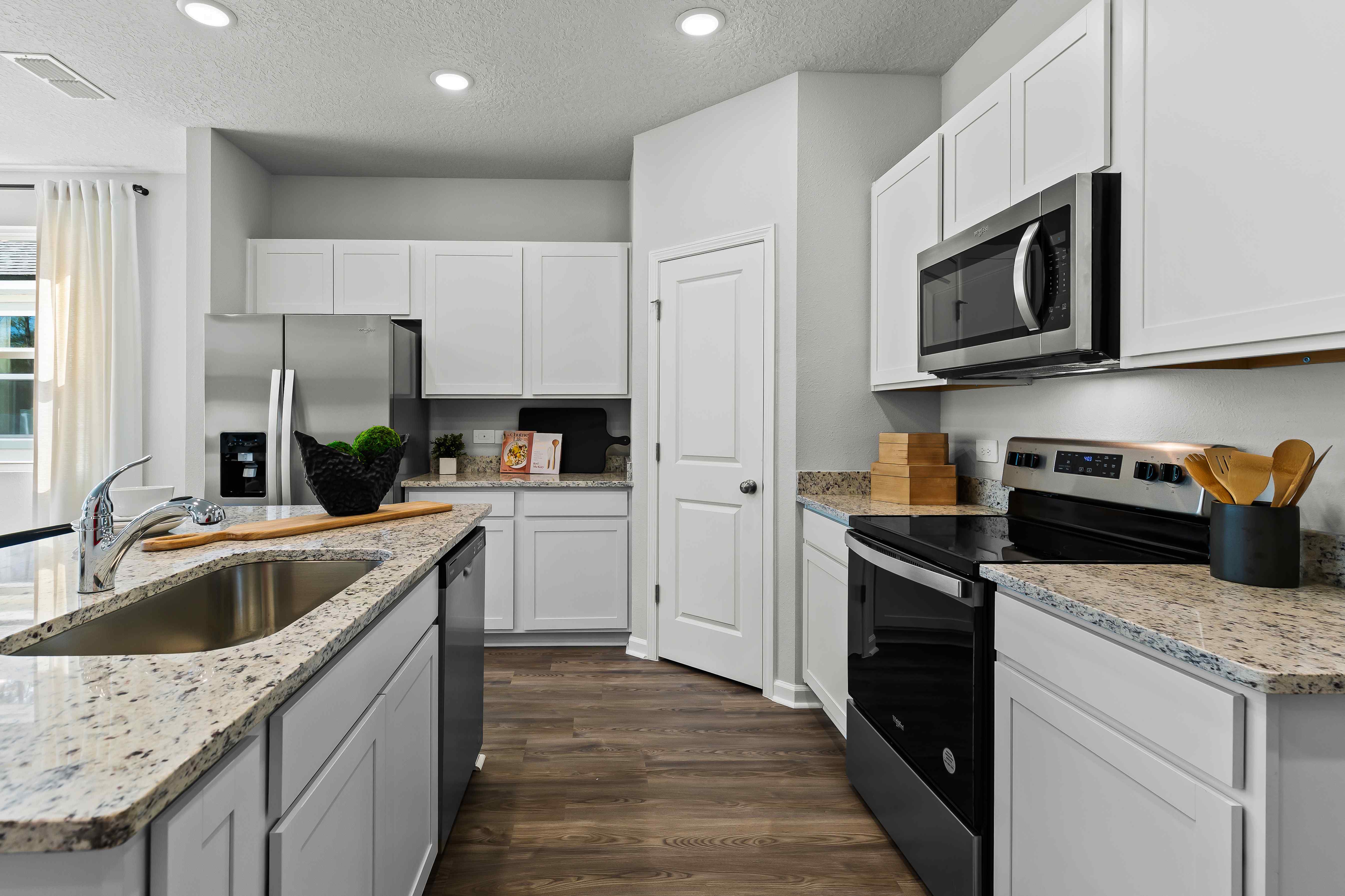 Davor Model Paired Home Kitchen with Marbled Counters and White Cabinets at The Landings at Pecan Park