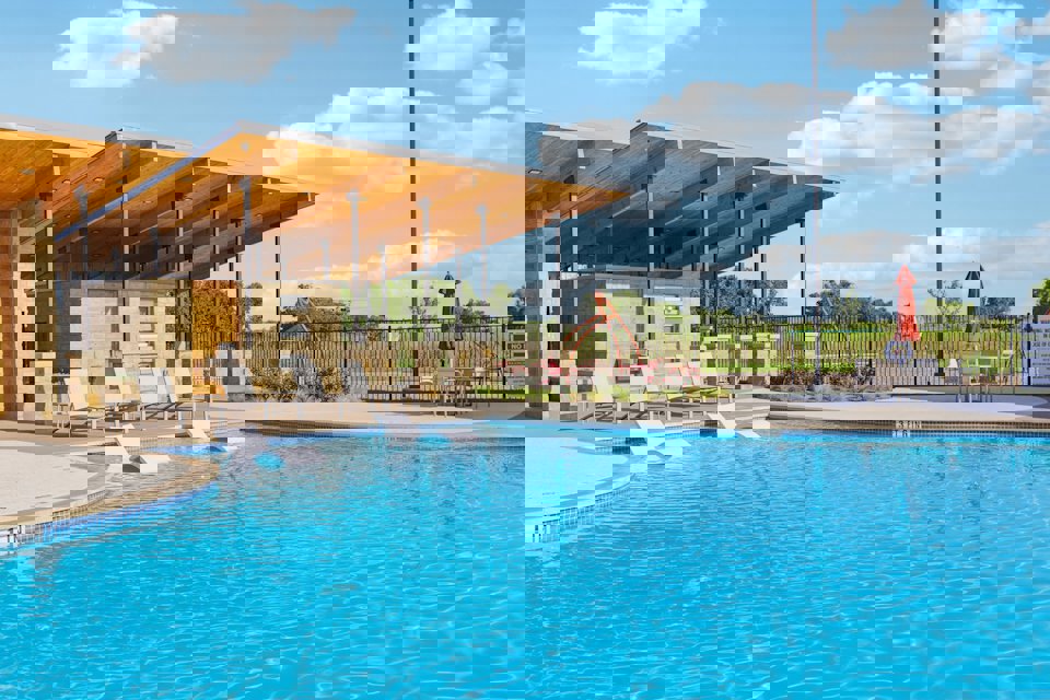 A swimming pool with chairs and umbrella.