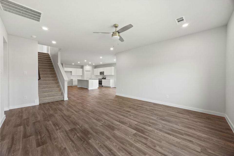 A large empty room with a wood floor and a ceiling fan.