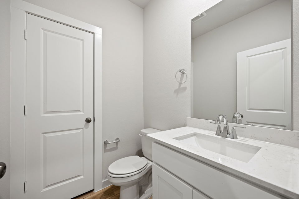 A bathroom with a sink toilet and mirror.