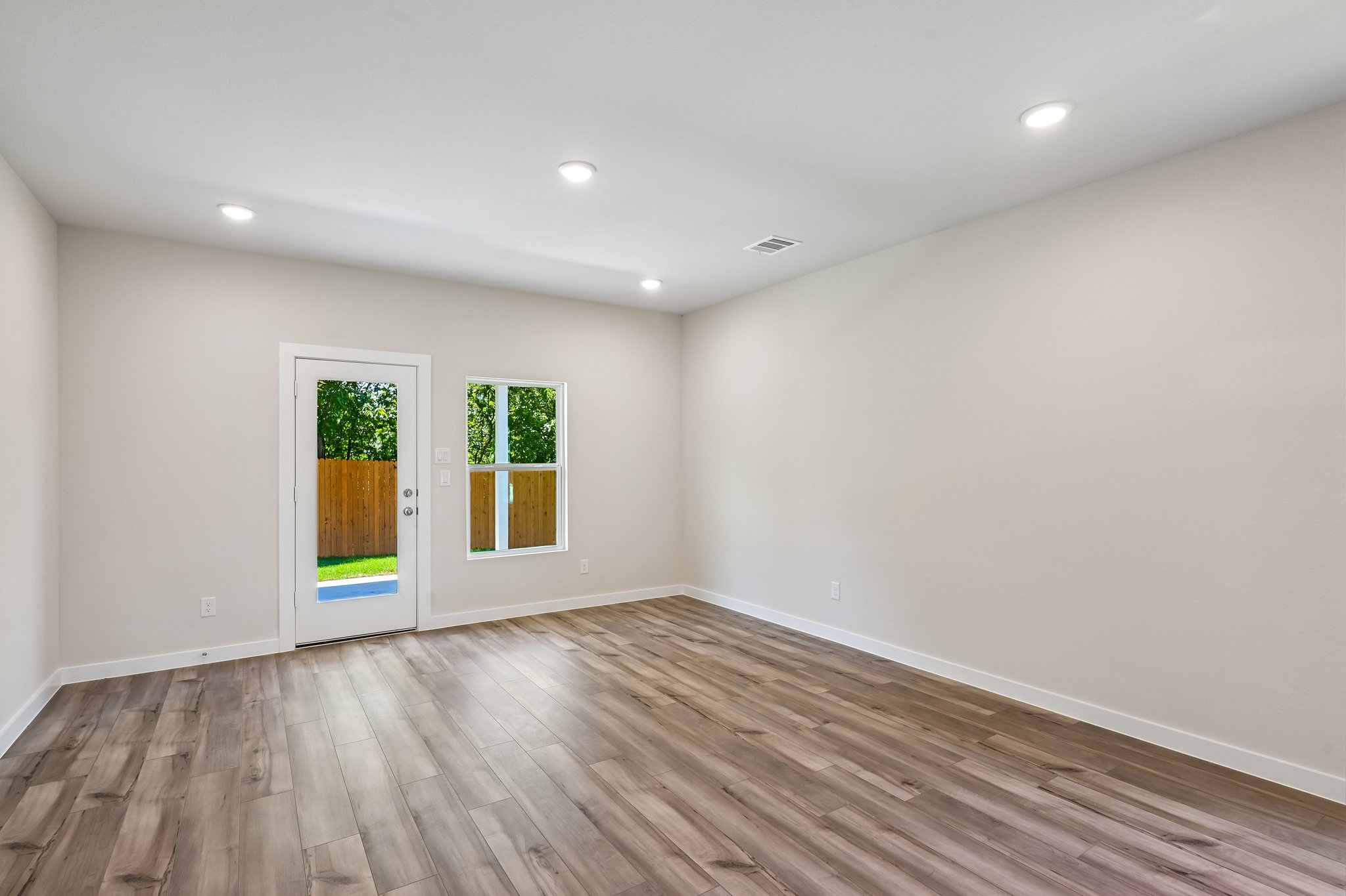 A room with a wood floor and a wood floor with a door.