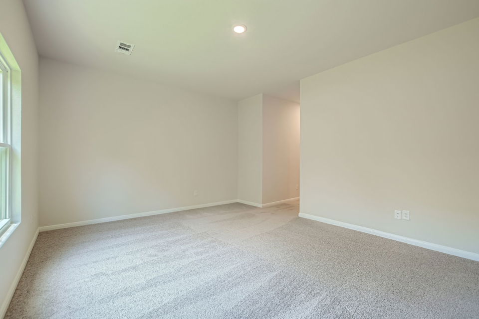 A room with a carpet and a light on the wall.