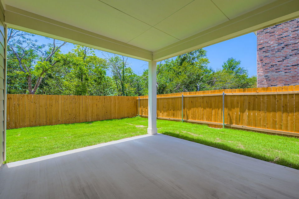 A fenced in area with a wood gate and trees in the background.