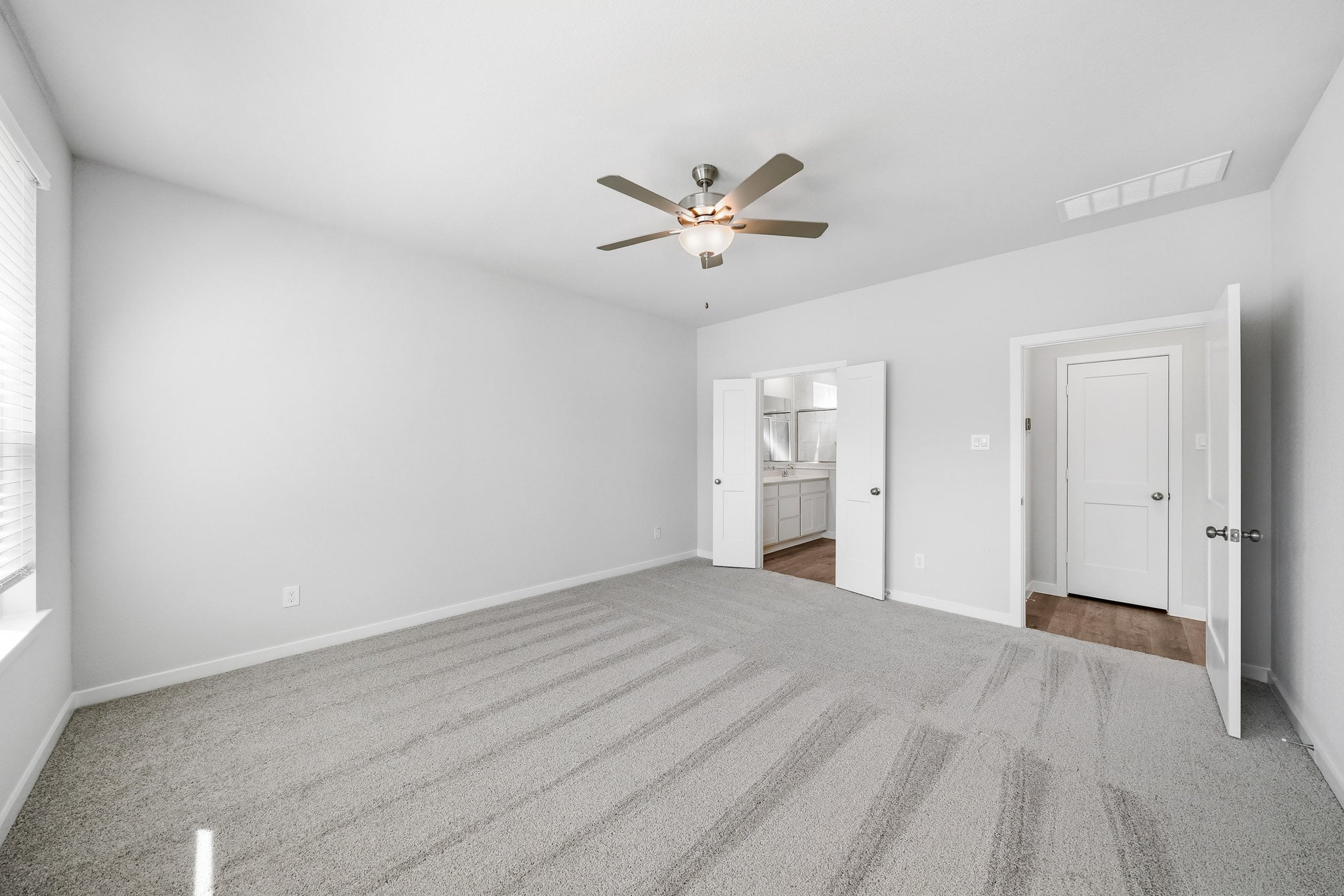 A room with a ceiling fan and a carpet.