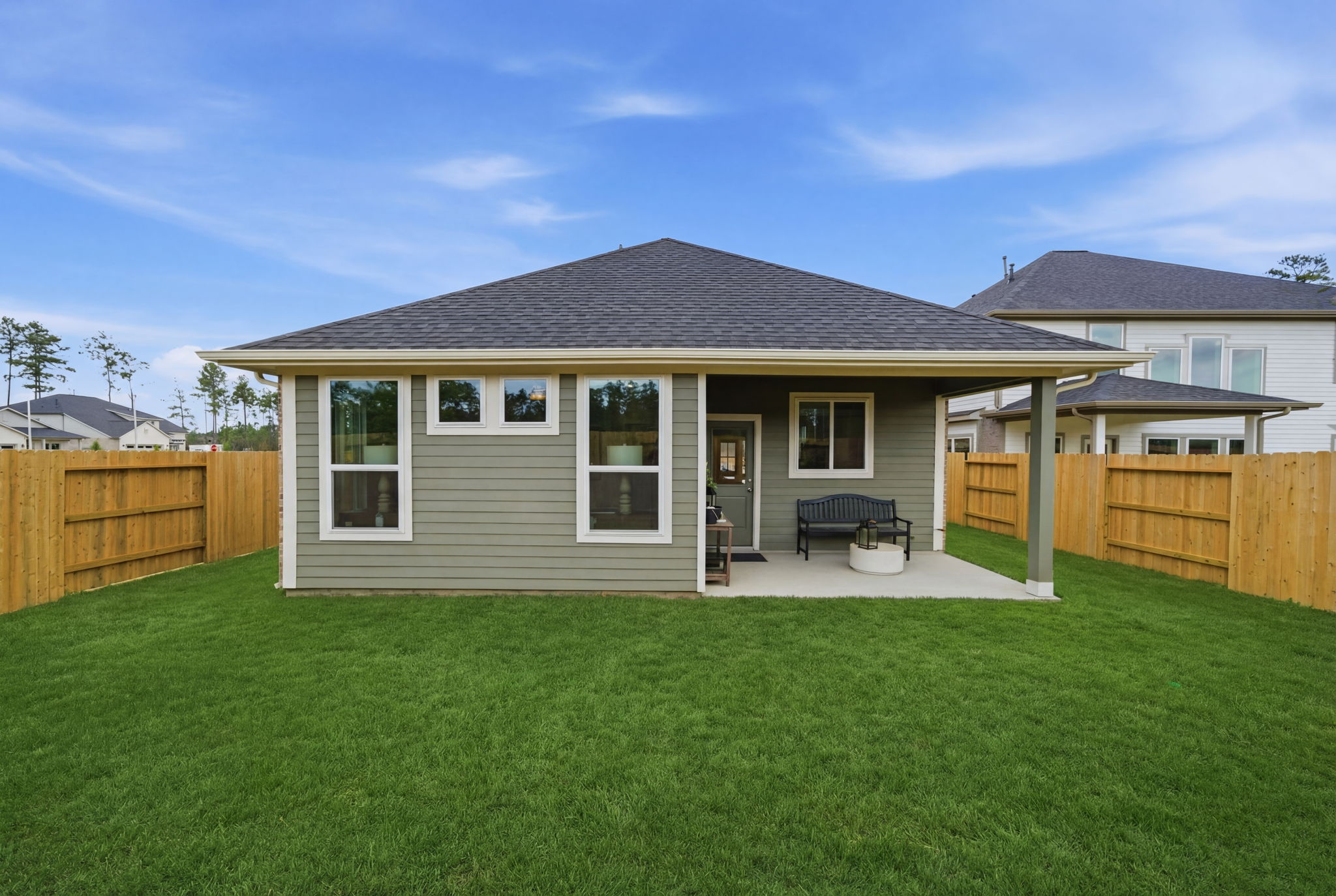A house with a fence and a lawn in front of it.