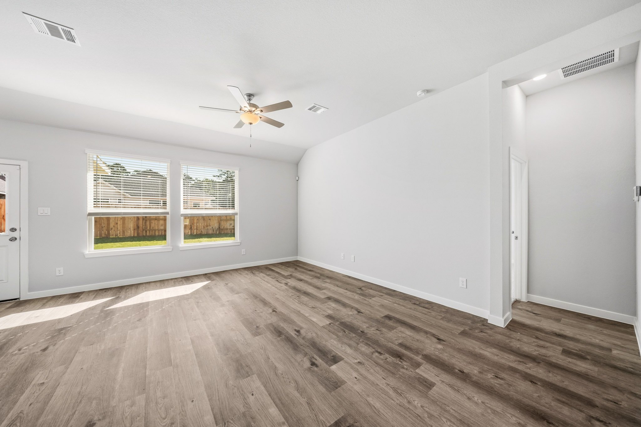 A room with a wood floor and a ceiling fan.