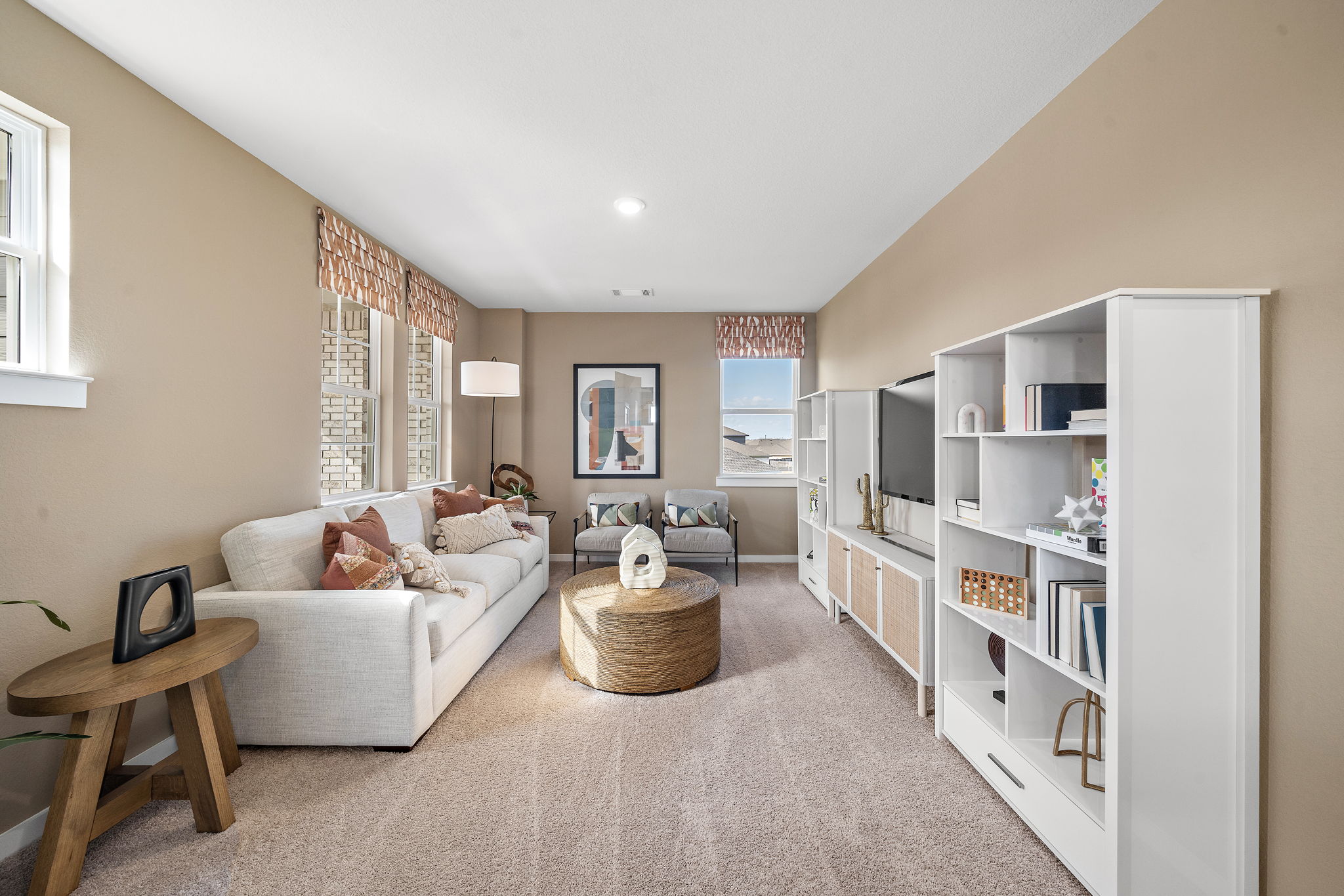 A living room with a white couch and a white bookcase.