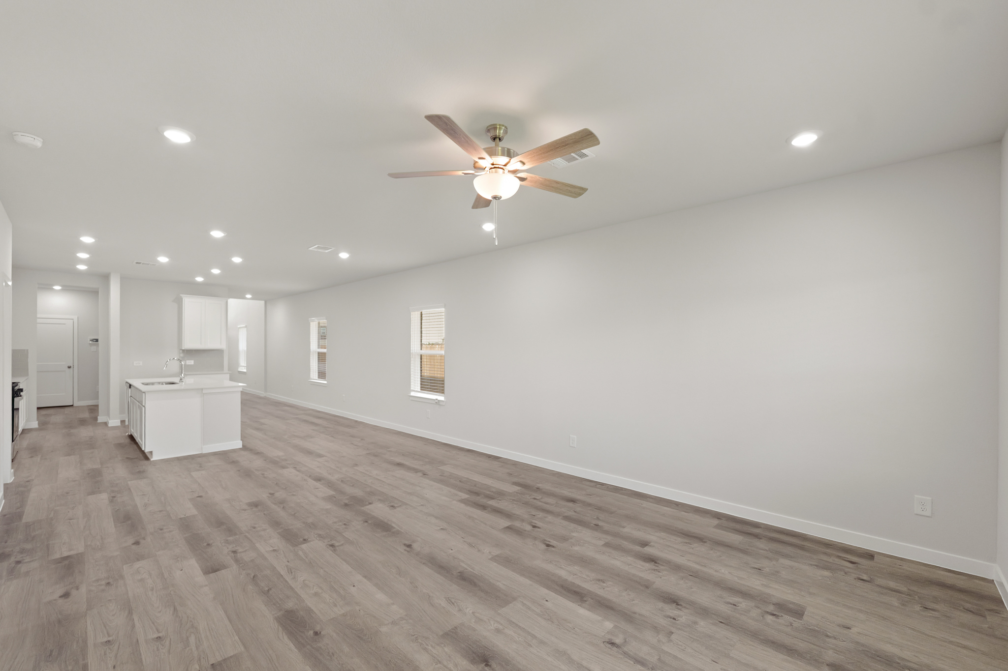 A room with a ceiling fan and a wood floor.