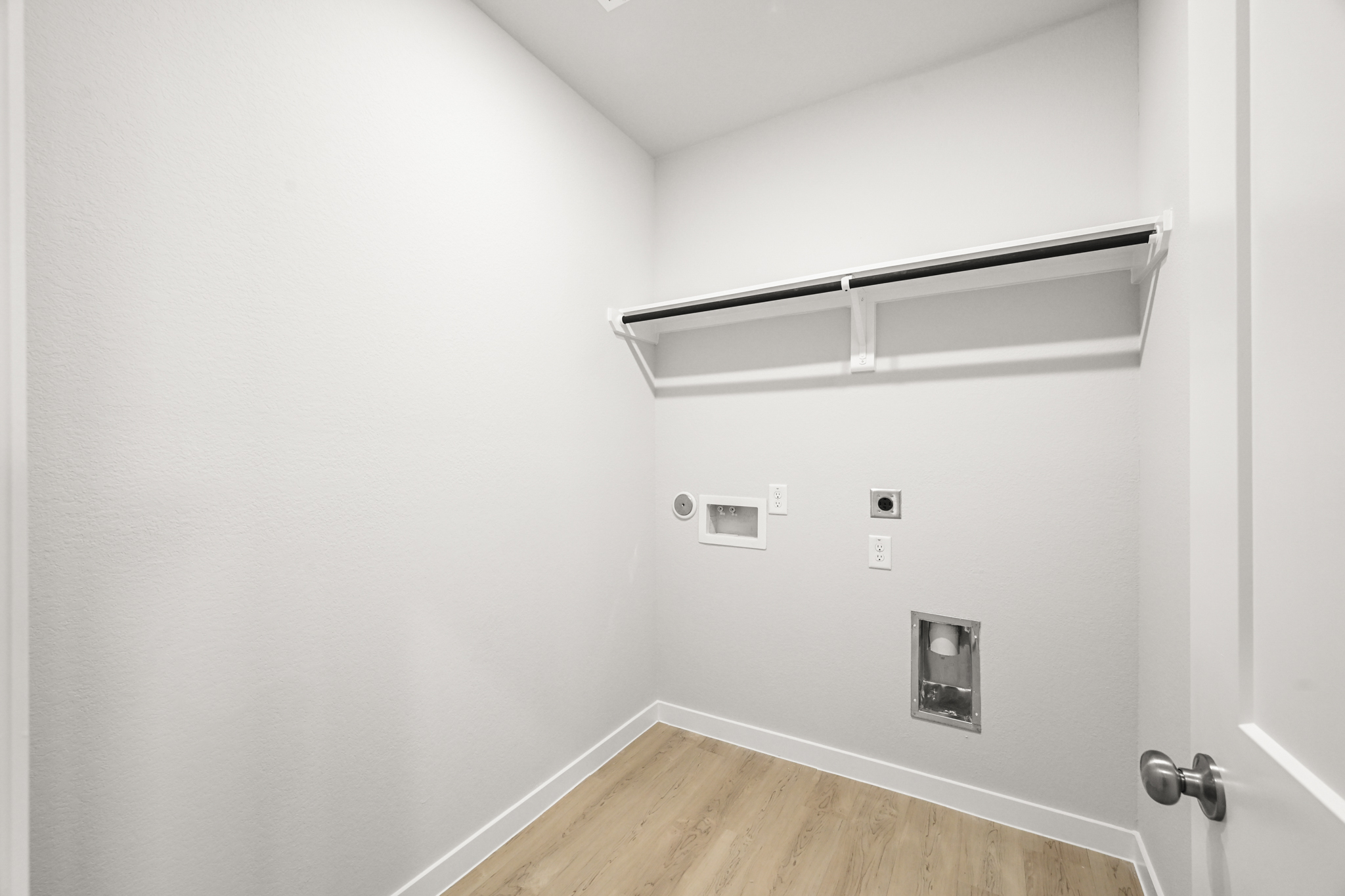A white room with a wood floor and a white door.