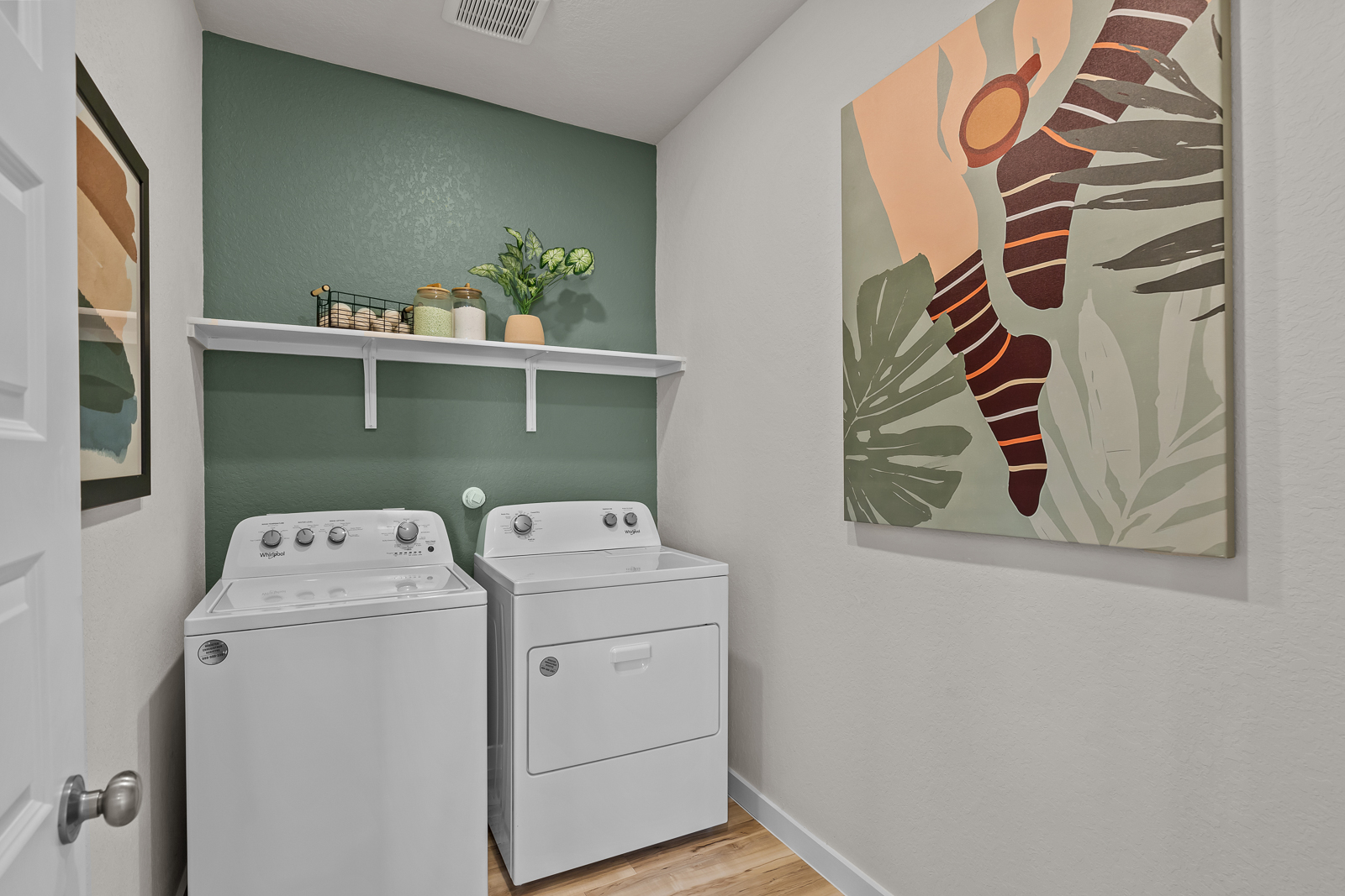 A laundry room with a painting on the wall.