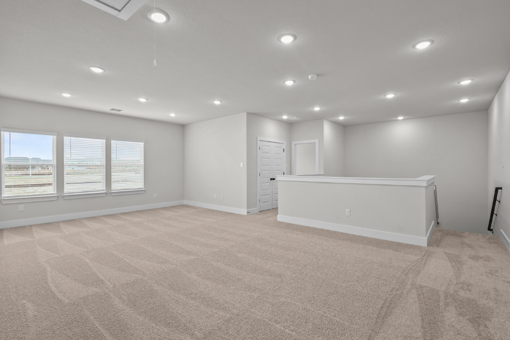 A large empty room with a white desk and a window.
