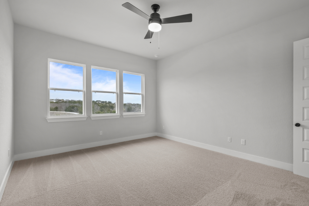 A room with a ceiling fan and windows.