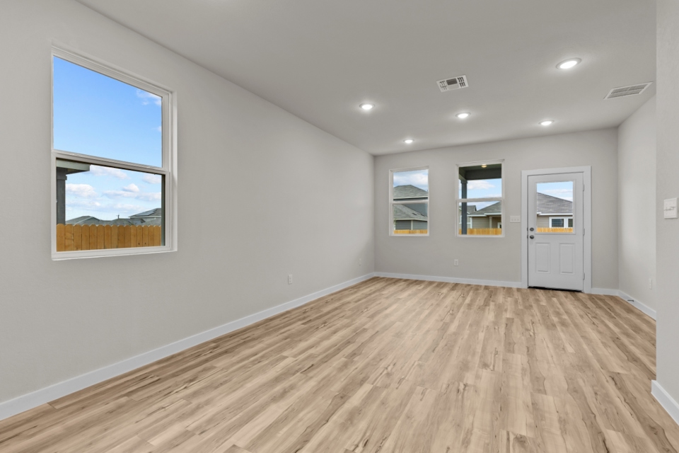 A room with a wood floor and a window with a view of the ocean.