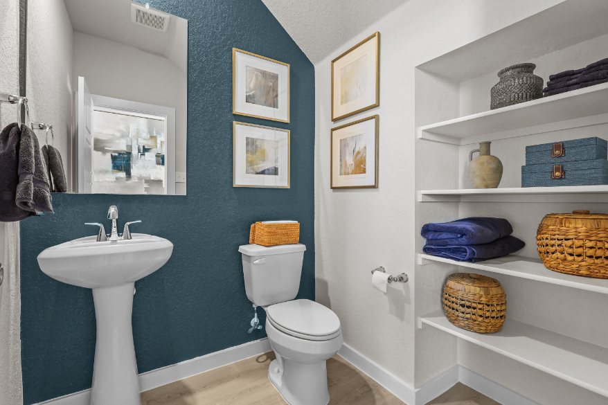 A bathroom with a sink toilet and shelves.
